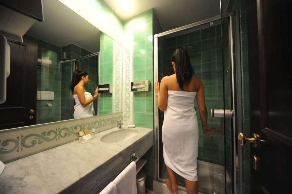 Un baño con cabina de ducha de vidrio, lavabo con espejo y toallero.
