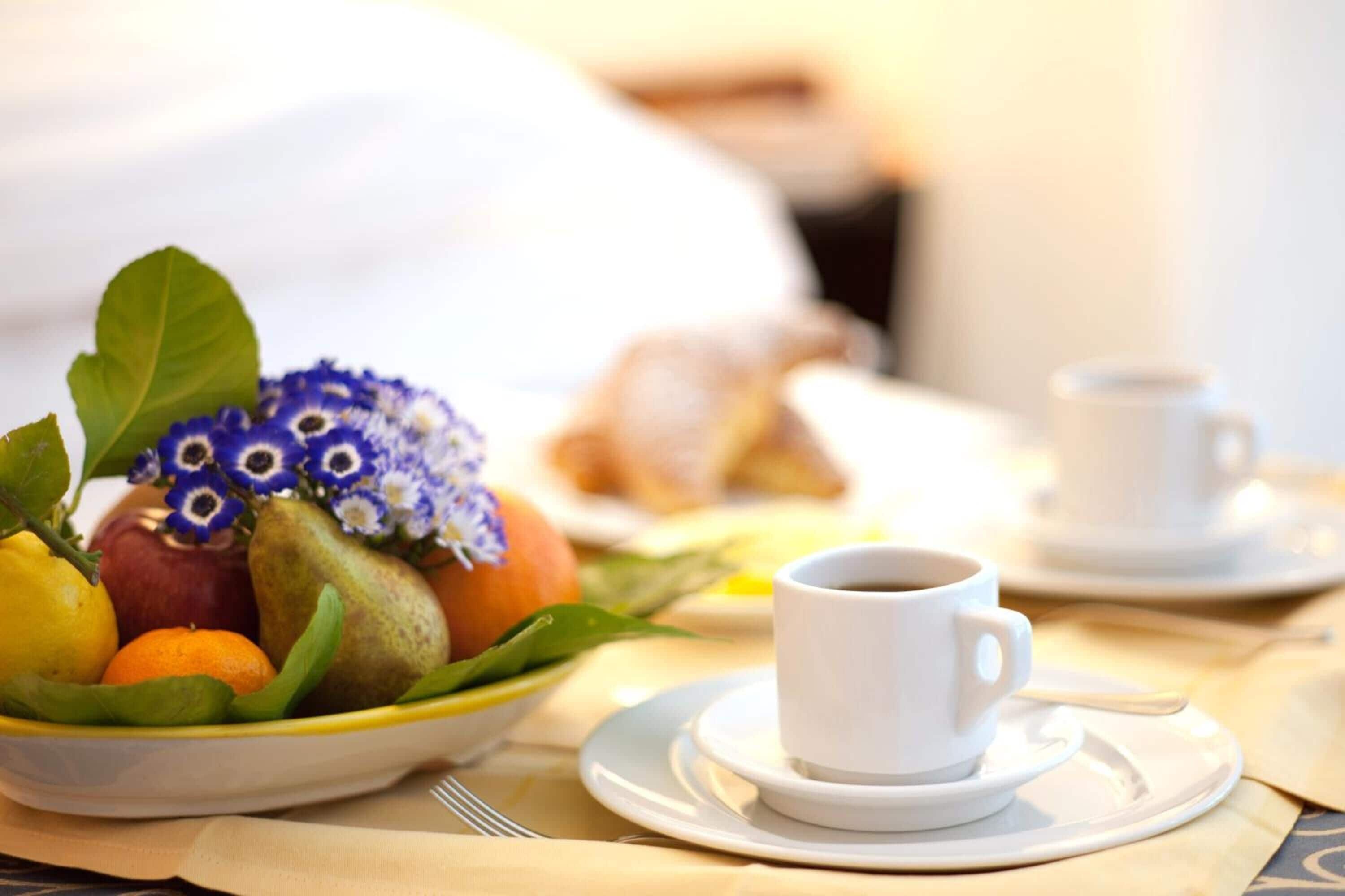 Ein Frühstückstisch mit Obstschale, Kaffeetasse und Croissants.
