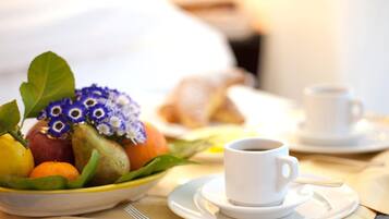 A breakfast setting with a bowl of fruit, a cup of coffee, and a plate of croissants.