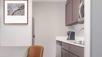 A modern kitchen with a dishwasher, a coffee machine, and a framed map on the wall.