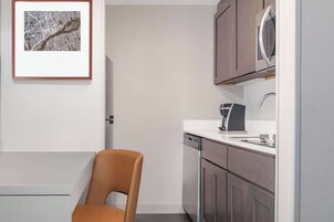 A modern kitchen with a dishwasher, a coffee machine, and a framed map on the wall.