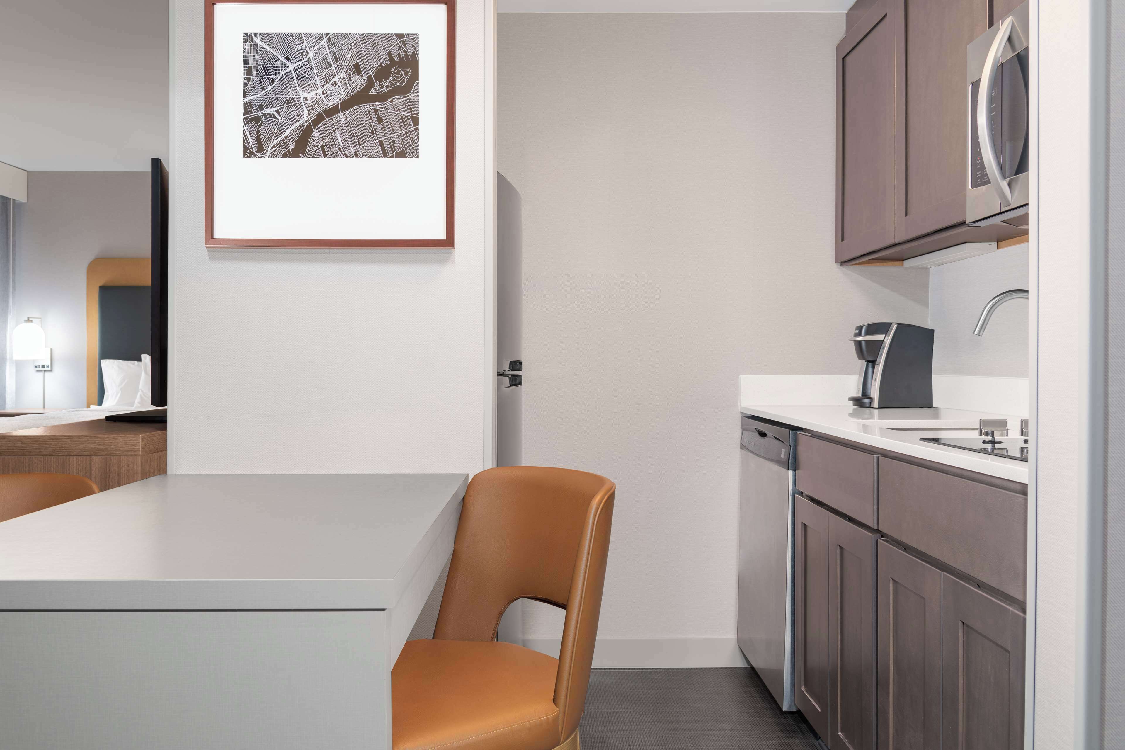 A modern kitchen with a white countertop, a coffee machine, and wooden cabinets.