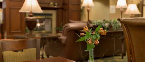 A dining area with a wooden table, chairs, and a vase with flowers.