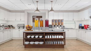A modern kitchen with white cabinets, a central island with shelves, and a coffee station. - Homewood Suites by Hilton Detroit-Troy (Troy)