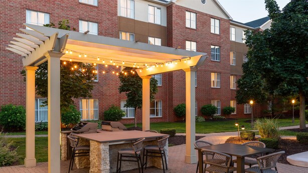 An outdoor patio with a grill, seating, and string lights. - Homewood Suites by Hilton Detroit-Troy (Troy)