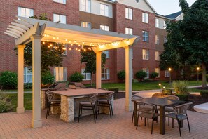 An outdoor patio with a grill, seating, and string lights. - Homewood Suites by Hilton Detroit-Troy (Troy)