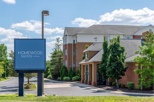 Letrero de hotel de Homewood Suites by Hilton, rodeado de un césped cuidado y árboles.