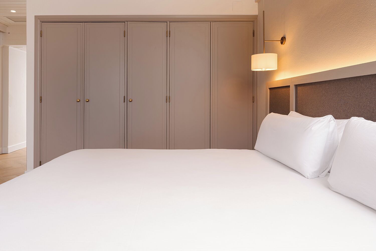 Une chambre à coucher avec un grand lit, une armoire et un luminaire fixé au mur.