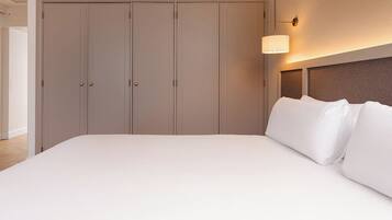 Une chambre à coucher avec un grand lit, une armoire et un luminaire fixé au mur.