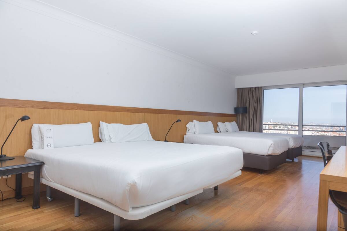 Une chambre d’hôtel avec deux lits, un bureau et une vue sur la ville.