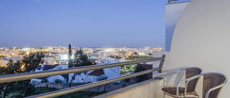 A balcony with a view of a cityscape at dusk.