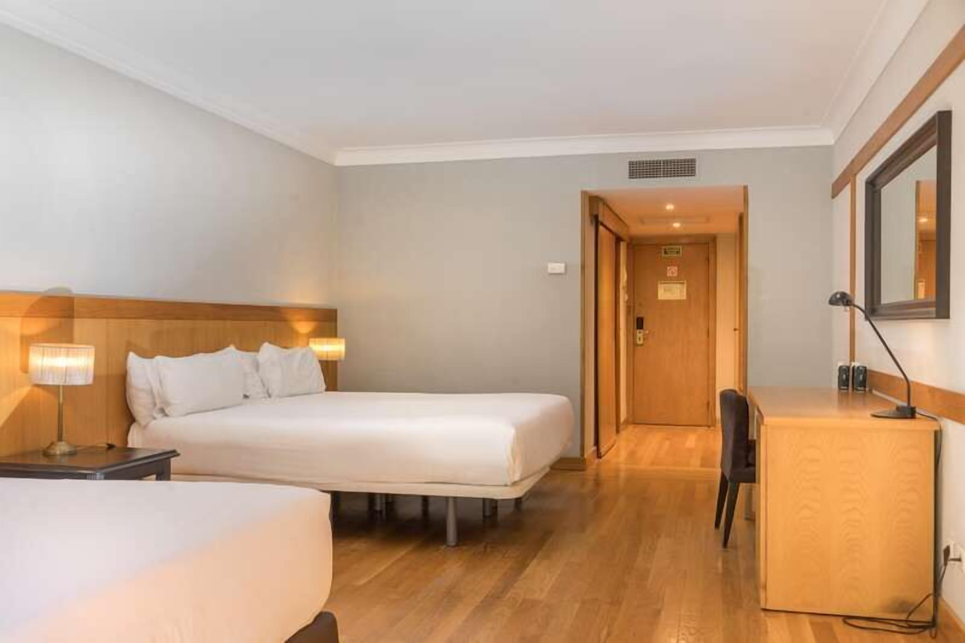 Ett hotellrum med två sängar, ett skrivbord och en stol.
