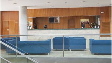 Una zona de recepción con pared de madera, mostrador, televisor de pantalla plana y asientos azules.