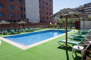 Una piscina al aire libre de temporada, sombrillas