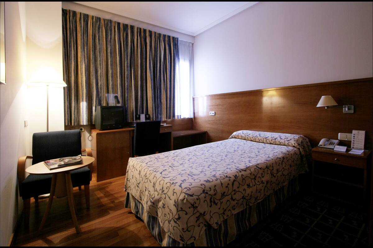 Une chambre d’hôtel équipée d’un lit, d’un bureau, d’une chaise, d’une lampe et d’un téléviseur.