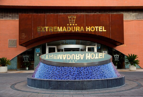 The entrance to the Extremadura Hotel with a prominent sign and a decorative tiled fountain in front.