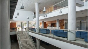 Een ruime lobby met een centrale trap, zithoeken en een receptiebalie.