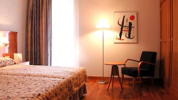 Habitación de hotel con cama, una silla, una lámpara y un cuadro en la pared.