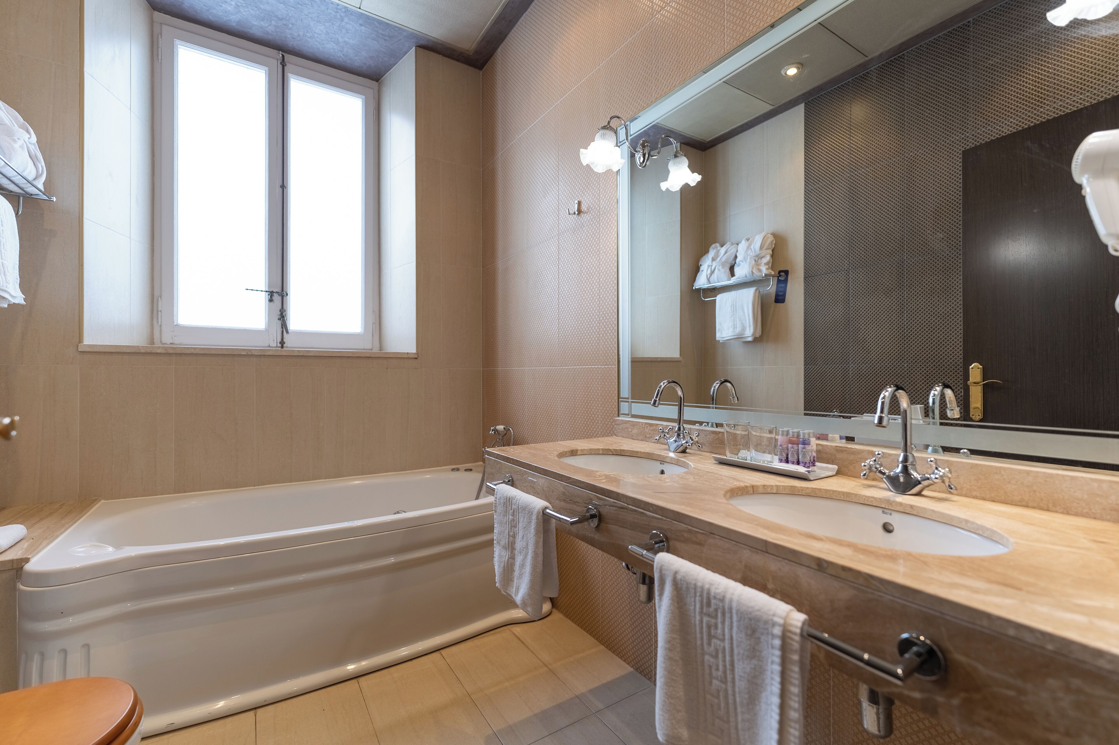 Un baño moderno con bañera, dos lavamanos y un espejo grande.