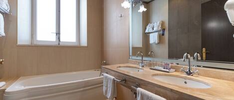 Un baño moderno con bañera, dos lavamanos y un espejo grande.