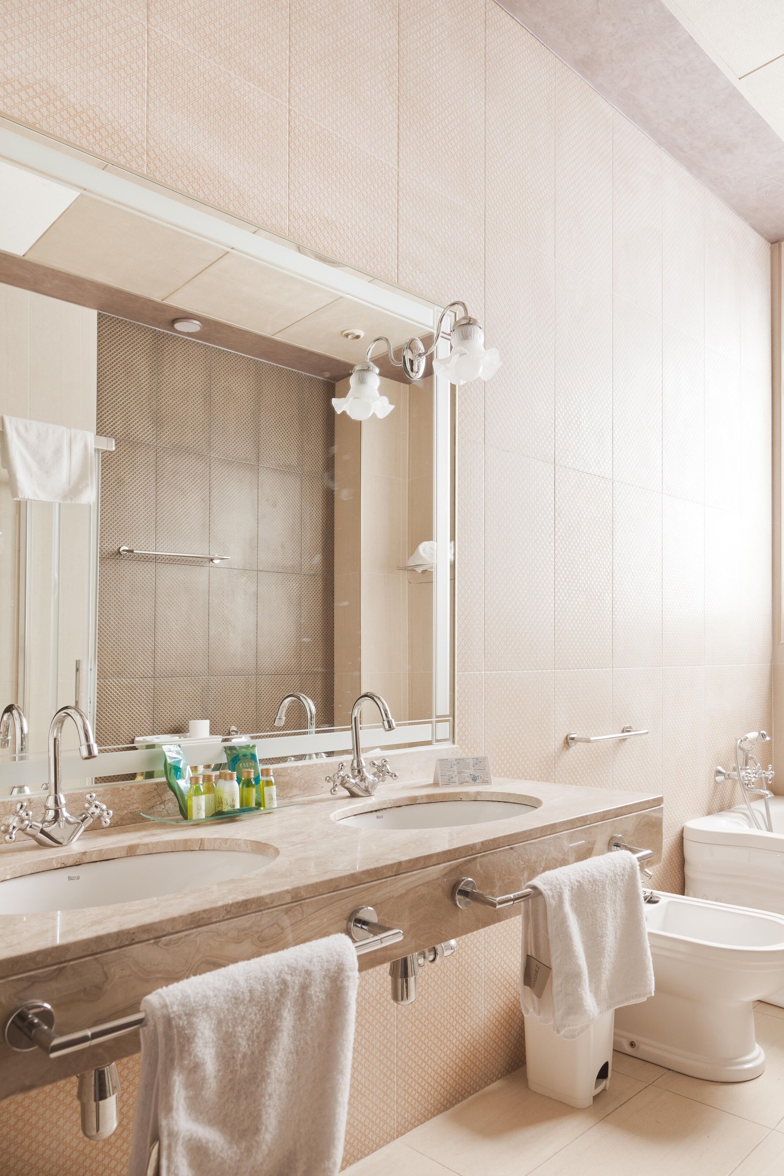 A modern bathroom with two sinks, a large mirror, and a toilet.