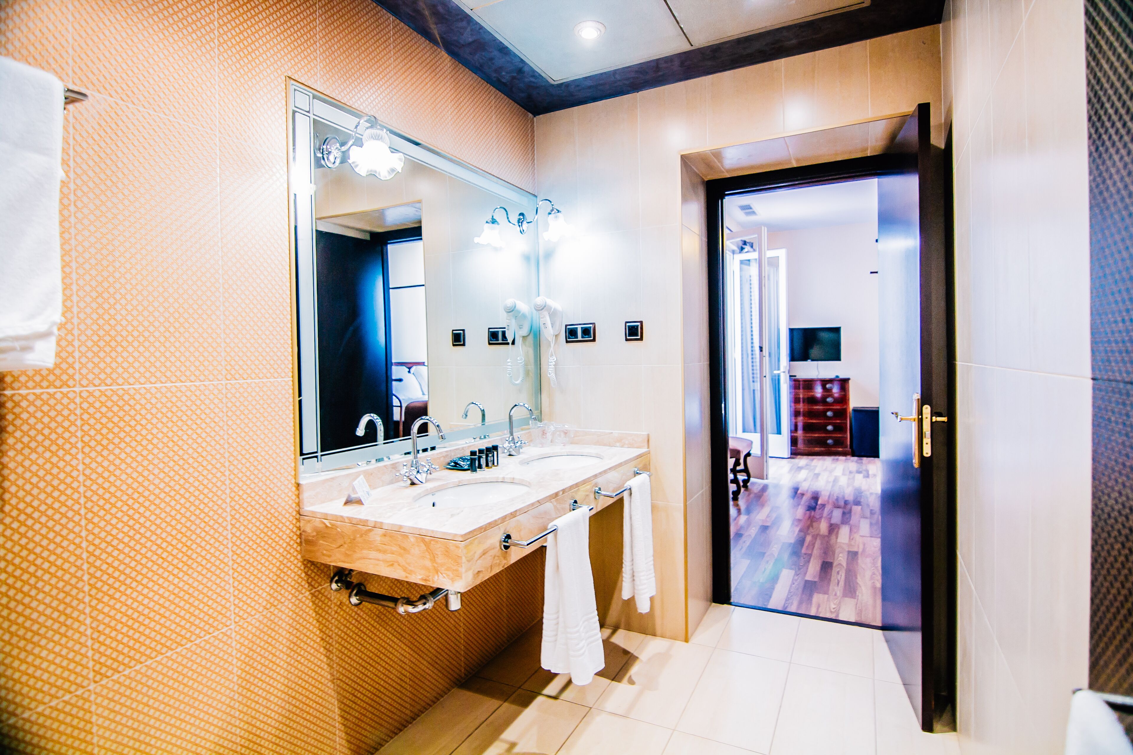A modern bathroom with two sinks, a large mirror, and a wooden vanity.