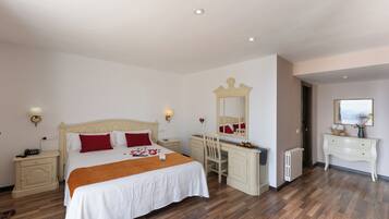 A neatly arranged bedroom with a large bed, a desk, and a dresser.