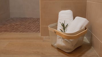 Ein Badezimmer mit einem Holzbadekorb, der zwei weiße Handtücher und eine grüne Pflanze enthält.
