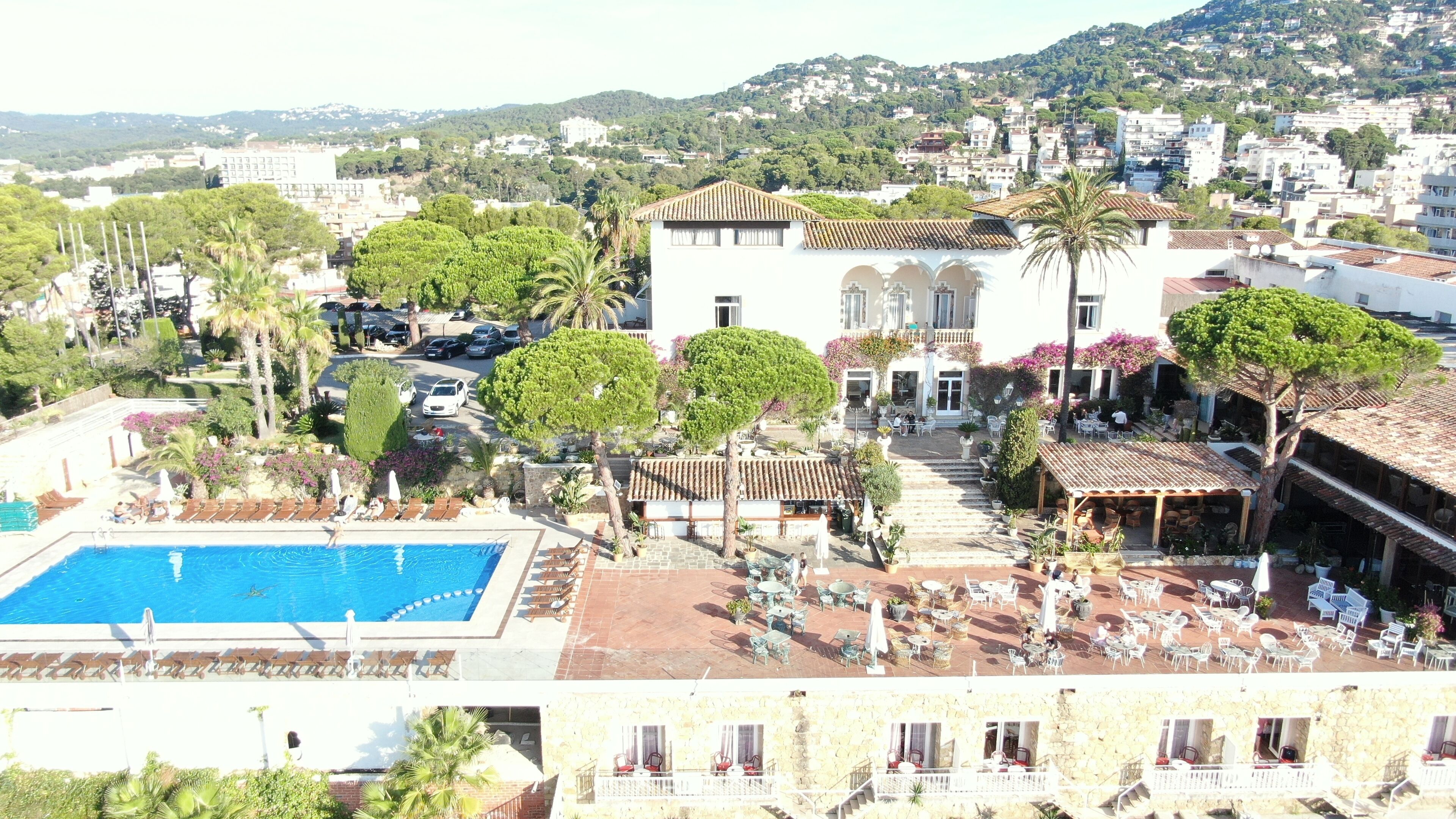 Un hotel con piscina, mobiliario exterior y vistas de la ciudad circundante.
