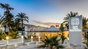 A hotel entrance with a sign reading "Hotel Vibra Cala Tarida," surrounded by palm trees and a well-lit pathway. - Hotel Vibra Cala Tarida (Sant Josep de sa Talaia)