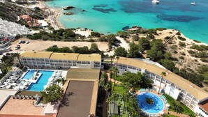 A resort with a swimming pool, a beach, and boats in the water. - Hotel Vibra Cala Tarida (Sant Josep de sa Talaia)