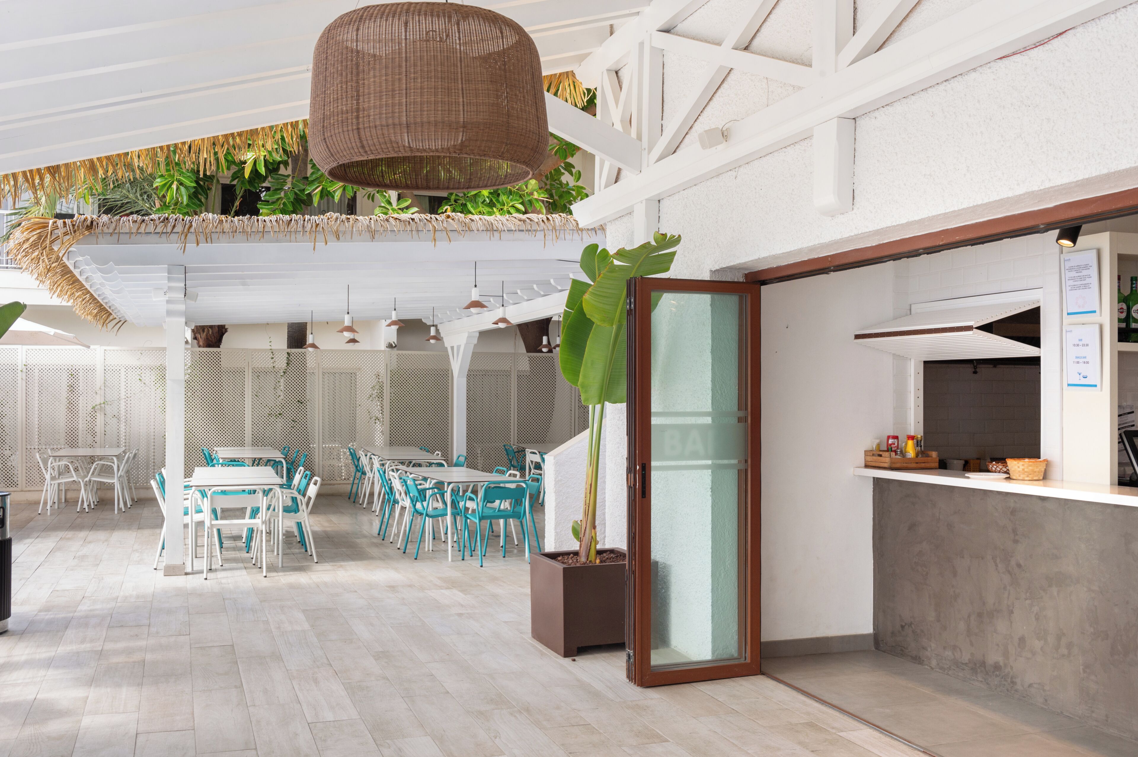 Ein Restaurant mit Terrassensitzgelegenheiten, einer großen Pflanze und einer Theke mit Speisekarte.