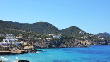 A coastal town with white buildings, a rocky shoreline, and clear blue waters.