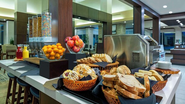 A buffet with various food items, including fruits, bread, and pastries. - Hilton Garden Inn Boise Spectrum (Boise)