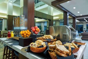 Un buffet proposant une variété de plats, notamment des fruits, du pain et des pâtisseries.