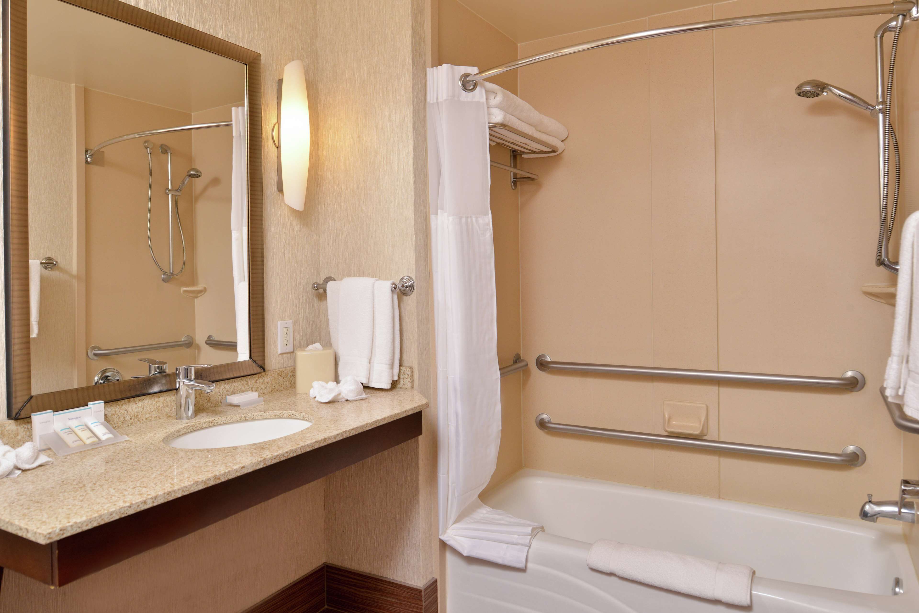 A bathroom with a sink, mirror, shower, and bathtub.