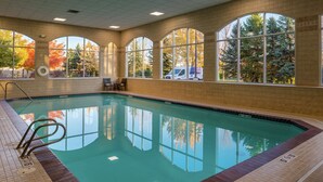 An indoor swimming pool with clear views through large arched windows, a lifeguard chair, and a pool ladder. - Hilton Garden Inn Boise Spectrum (Boise)
