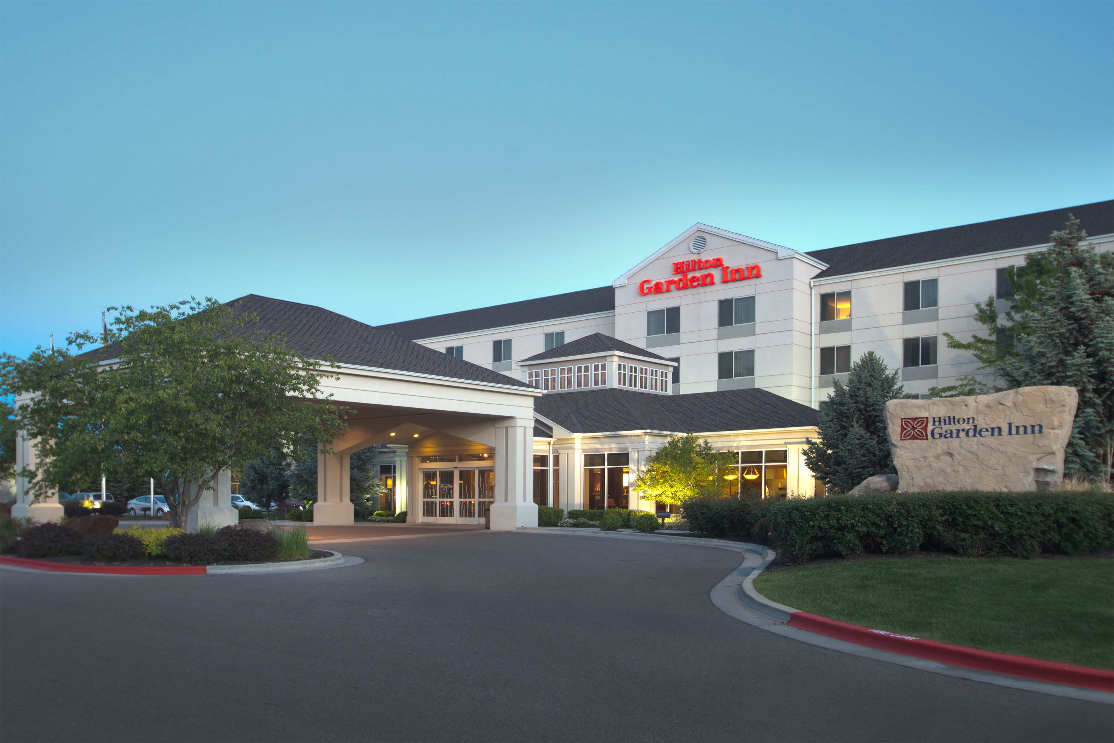 Un hôtel Hilton Garden Inn doté d’une grande entrée, d’une pelouse bien entretenue et offrant une vue sur un ciel dégagé.