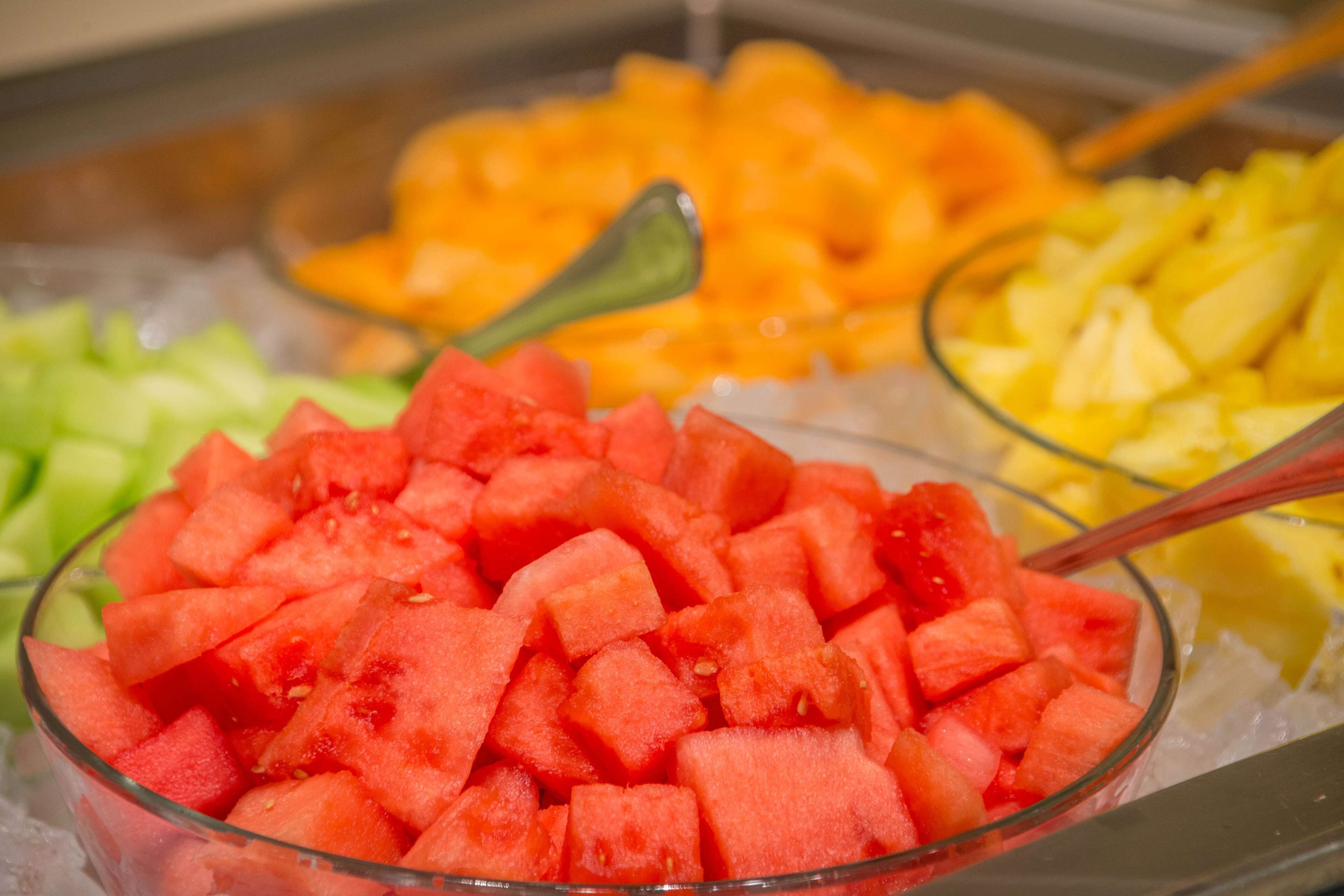 A buffet with various fruits including watermelon, oranges, and pineapple.
