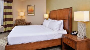 A hotel room with a wooden bed, two bedside lamps, a telephone, and a chair.