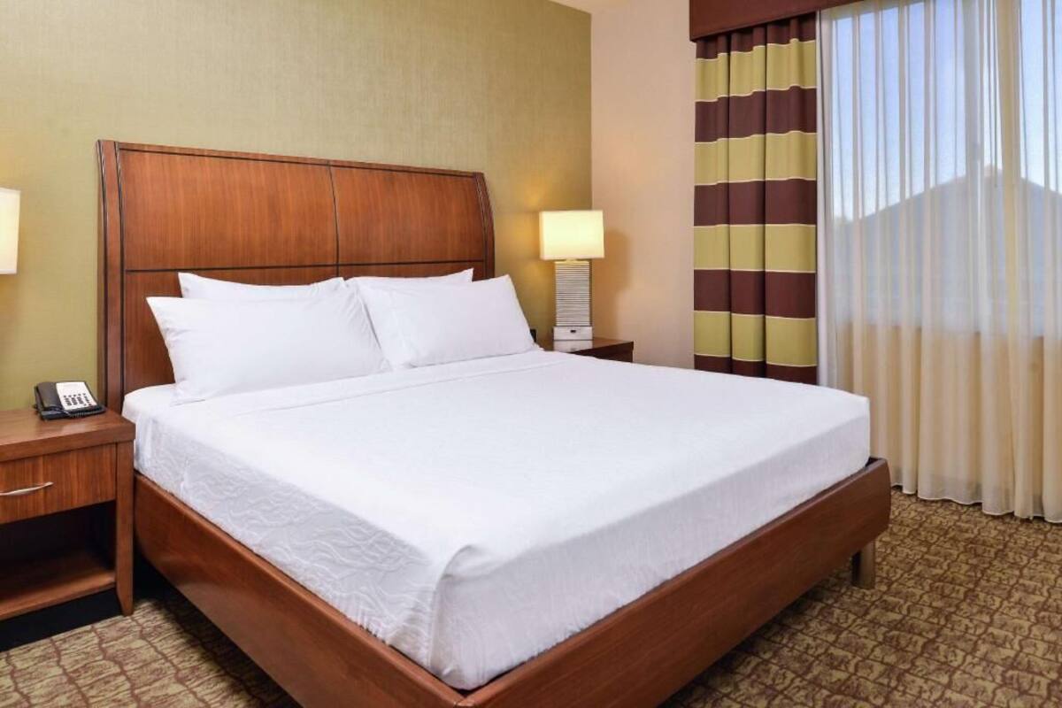 A hotel room with a large bed, a bedside table with a lamp, and a telephone.