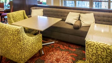 Un área de estar con un sofá, dos sillones y una mesa.