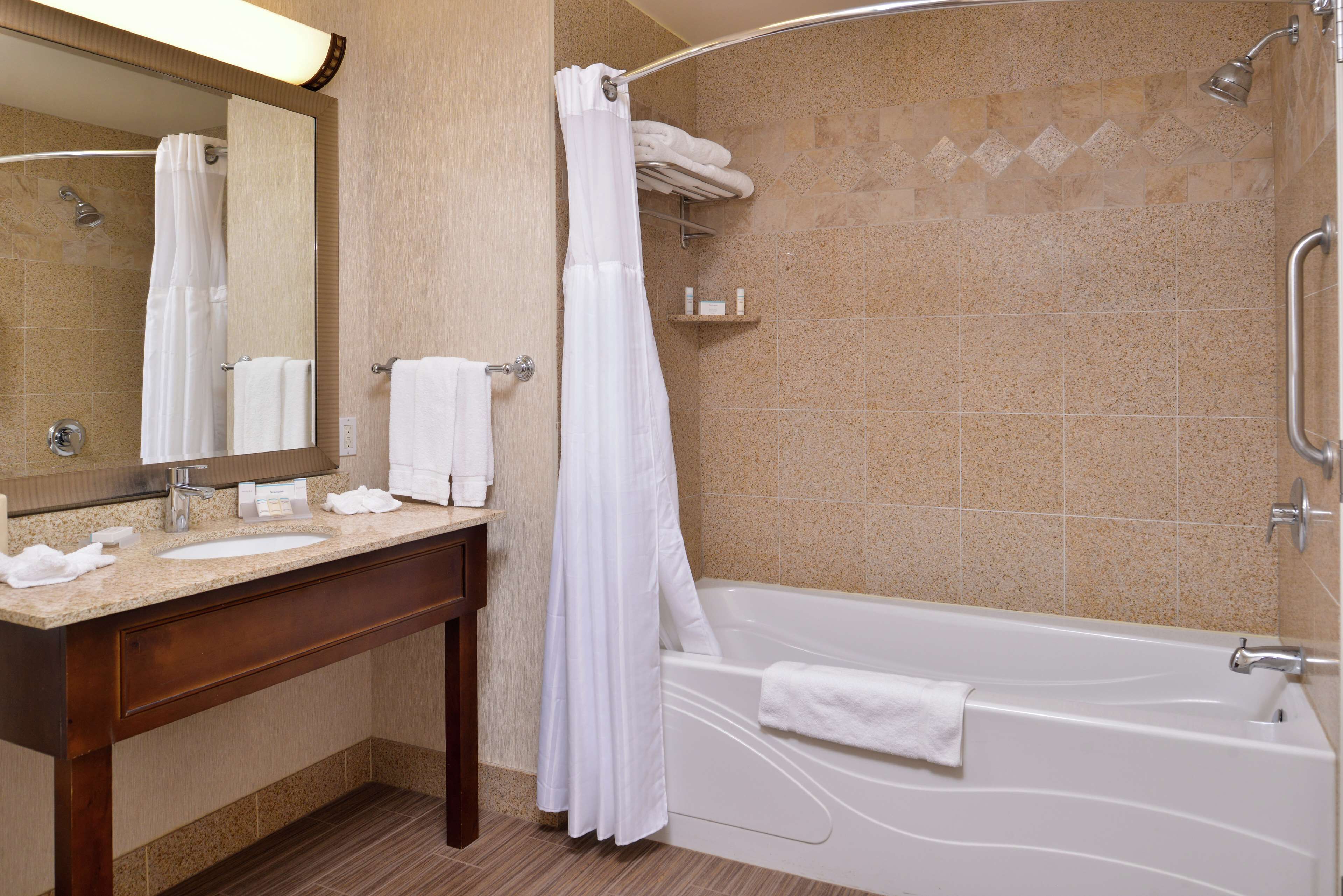 A bathroom with a bathtub, a sink, a mirror, and a shower curtain.