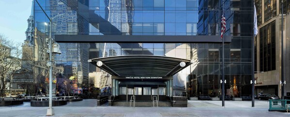 A modern hotel entrance with a glass facade reflecting surrounding buildings. - M Social Hotel New York Downtown  (New York)
