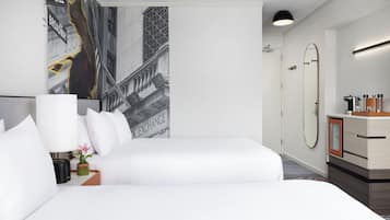 Hotelkamer met een groot bed, nachtkastje met lamp, spiegel en uitzicht op een gebouw met een bord waarop