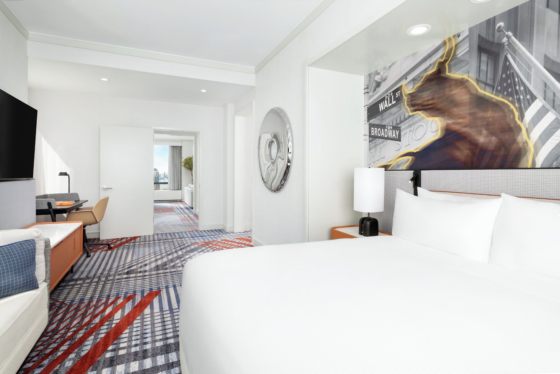 Habitación de hotel con una cama grande, un escritorio, una silla, un televisor y vistas a la ciudad.