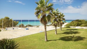 A beach volleyball court with a net, palm trees, and a view of the ocean. - Insotel Club Maryland (Formentera)