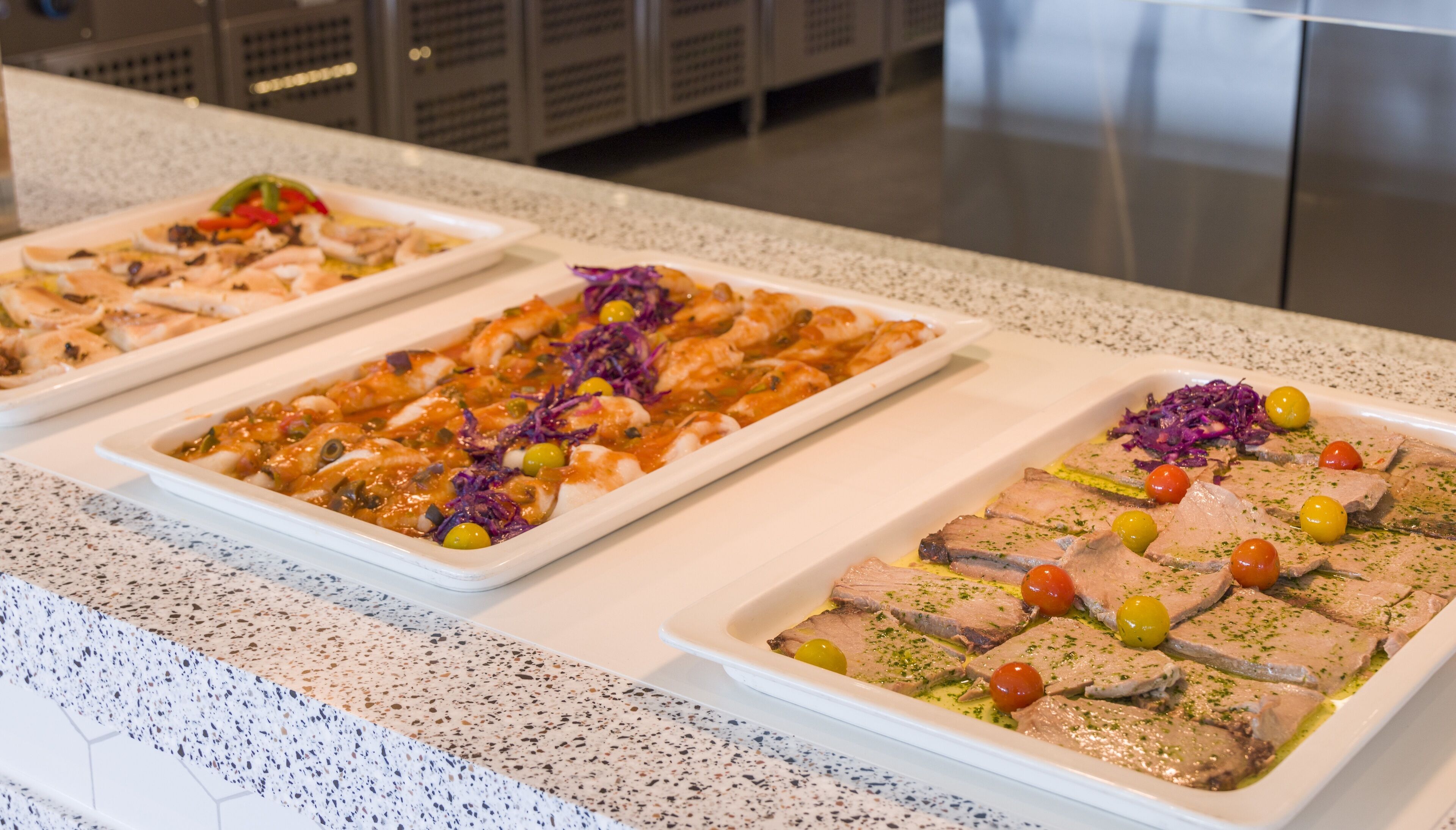 Una mesa de buffet con diversos platos, incluyendo mariscos y verduras, dispuestas sobre una encimera moteada.