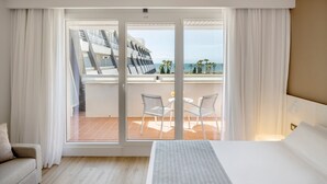 A hotel room with a balcony, a bed, a sofa, and a table with chairs. - Hotel ILUNION Islantilla (Islantilla)