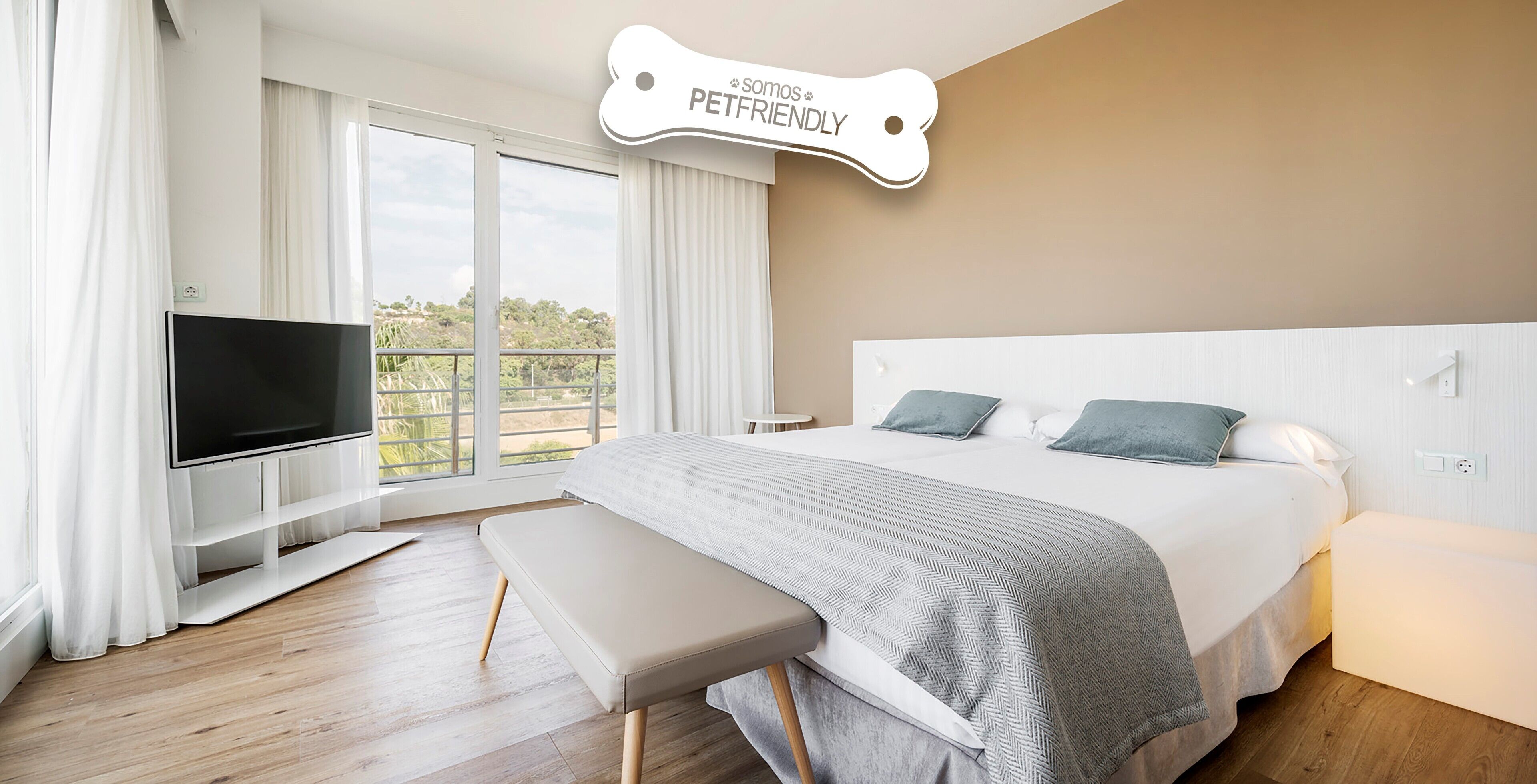 Una habitación de hotel moderna con una cama grande, un televisor, un banco y un balcón con cortinas.